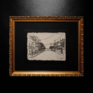 An ink drawing of a city street on deckle-edged paper, matted in black and framed in a classic gold ornate frame against a dark wall.