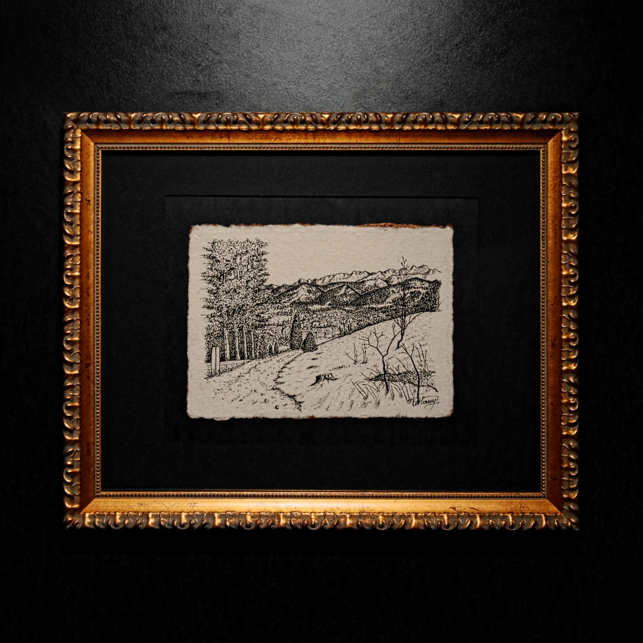 An ink mountain landscape drawing with deckled edges, set in a black mat and an ornate gold frame against a dark wall.