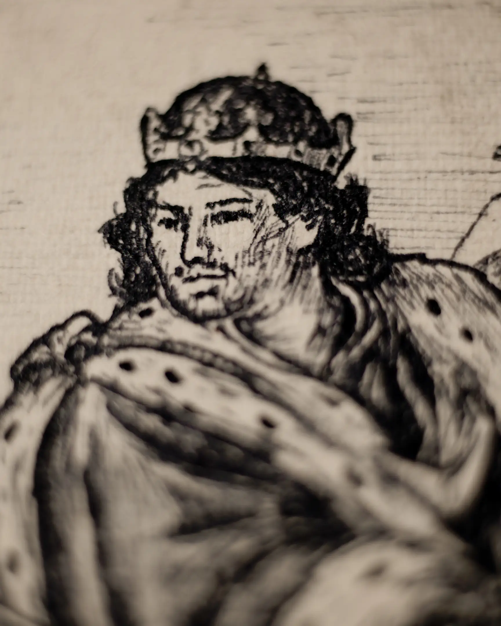 This fragment captures the head of the protagonist in profile, looking upwards and to the right. He wears a dark, pointed hood with dense, vertical ink hatching. The lighting highlights the weathered features of his face, his open eye, and the intense expression of longing. The background is composed of dark, blurry textures of the artwork's paper and ink