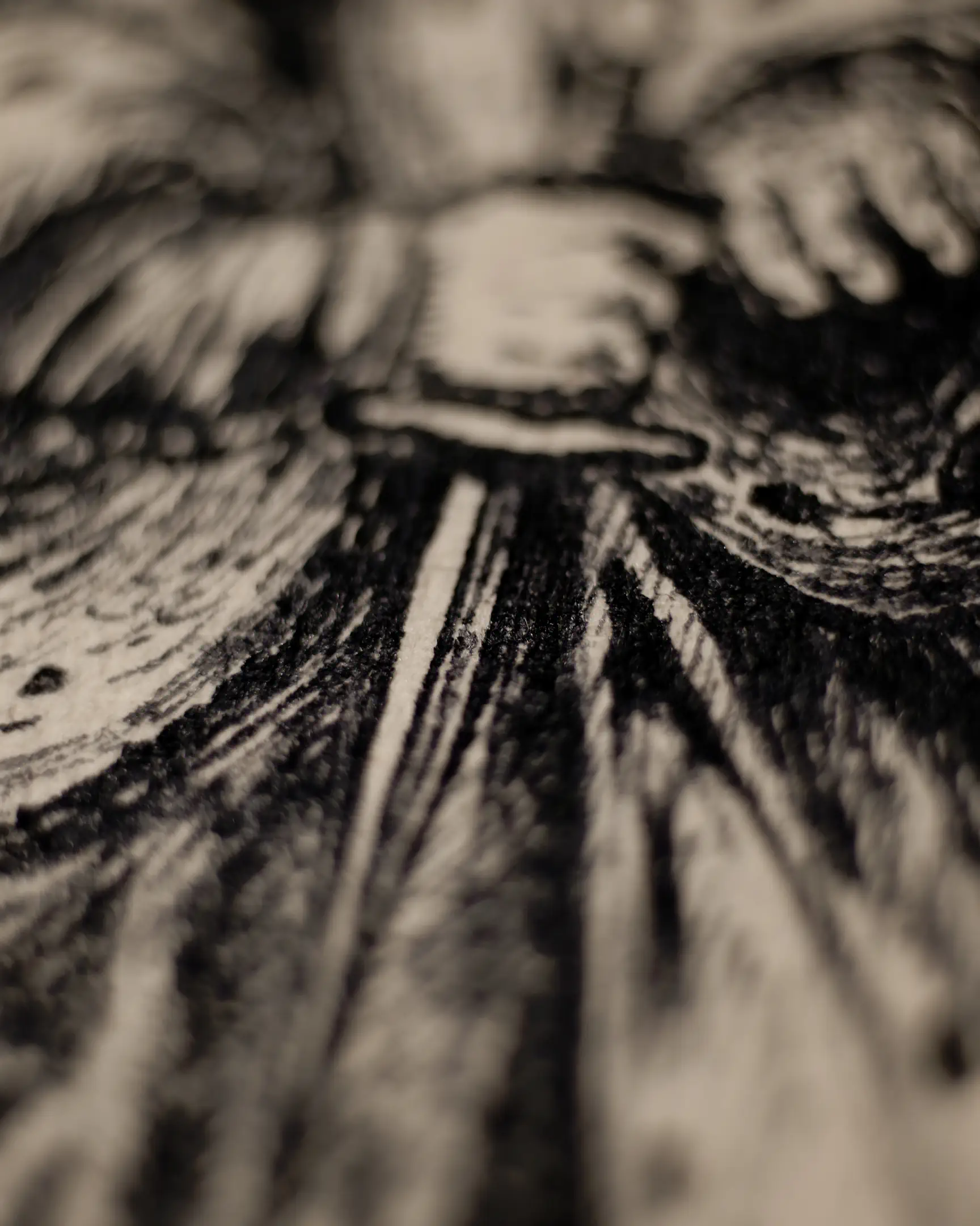 This fragment shows a hand firmly gripping a horizontal bar, which appears to be the hilt of a sword or a handle. The background and the area below the hand are filled with dense, vertical and diagonal ink hatching. The lighting emphasizes the depth of the ink on the textured surface, and the shallow depth of field keeps the focus strictly on the point of contact between the hand and the object.