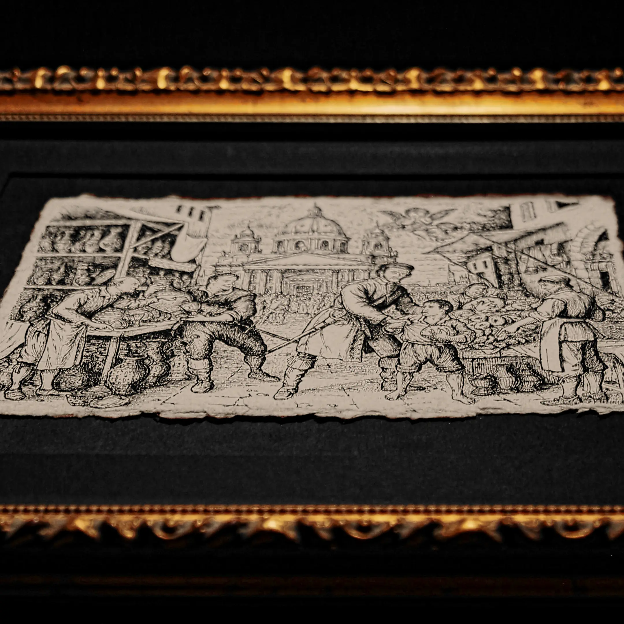 A perspective view of a classical ink drawing on thick, deckled-edge paper, mounted on a black mat inside a deep ornate gold frame.